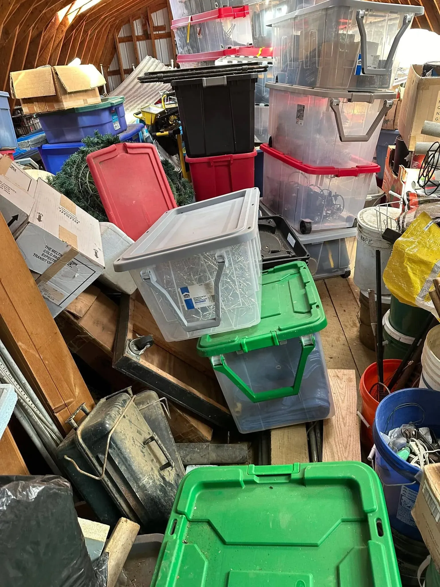 Crowded storage area filled with plastic bins, boxes, tools and other belongings before a real estate cleanout
